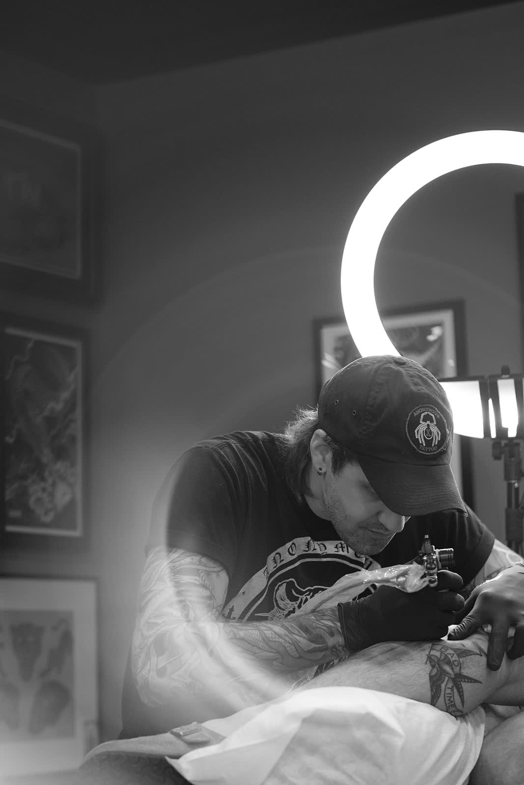 Christopher Cousins tattooing under a ring light