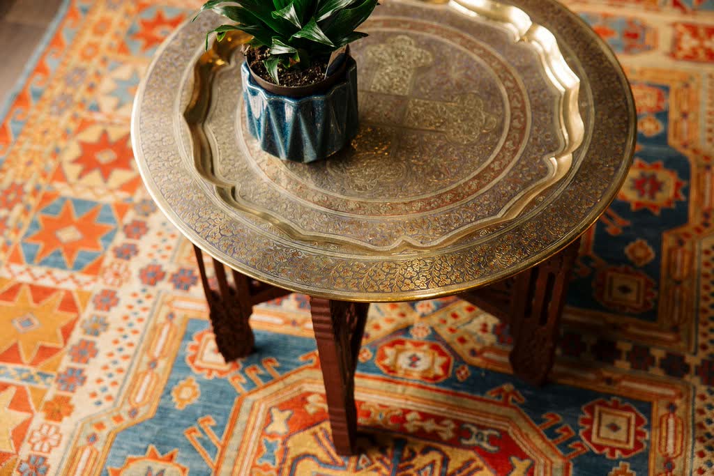 A brass tray table and plant on the rug in the studio's lounge